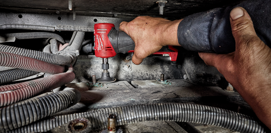 A person using a Milwaukee die grinder M12 to grind away corrosion around a bolt