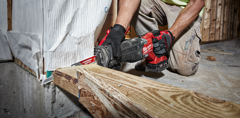 Someone cutting through a piece of wood with a Milwaukee Sawzall.