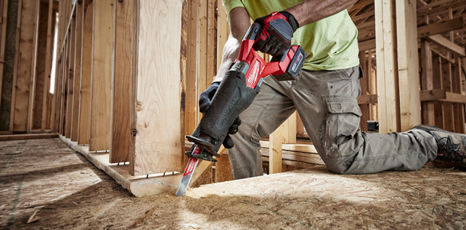 A construction worker using a Milwaukee M18 Fuel Sawzall to cut through a piece of wood