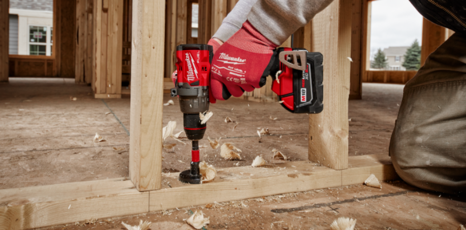 A worker using a Milwaukee M18 Fuel Drill to drill a hole into a piece of wood