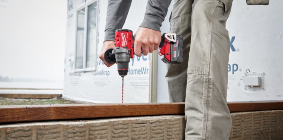 Worker using a Milwaukee hammer drill to drill a hole