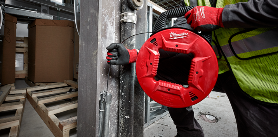 Person using a Milwaukee Fish Tape to pull a wire through a conduit