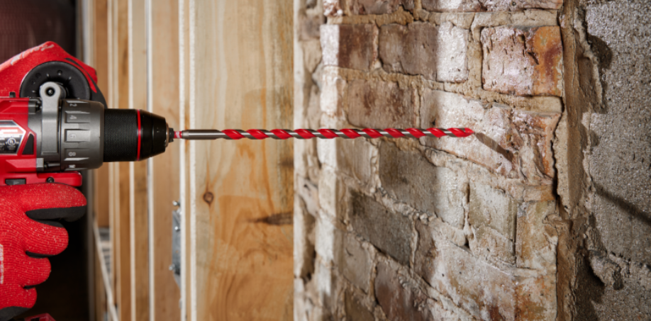 A carbide drill bit drilling into a brick wall