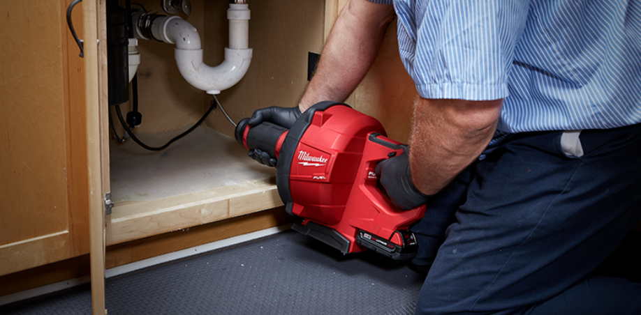 Someone using a Milwaukee Drain Snake to clean sink pipes