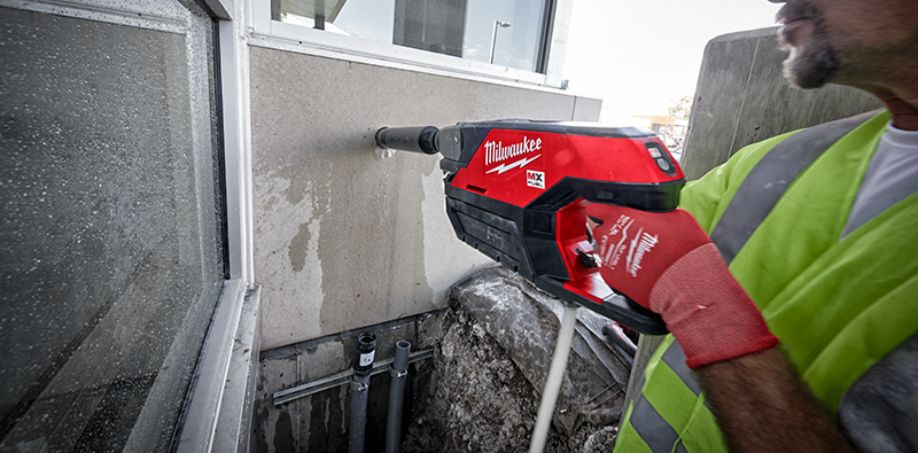 A picture of someone using a Milwaukee core drill to drill a hole into concrete