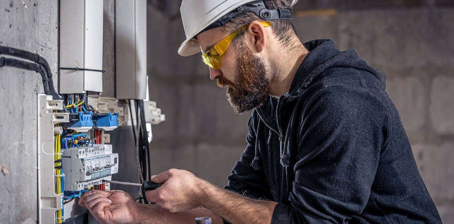 Electrician using an insulated screwdriver to fasten in a screw on the electrical breaker.