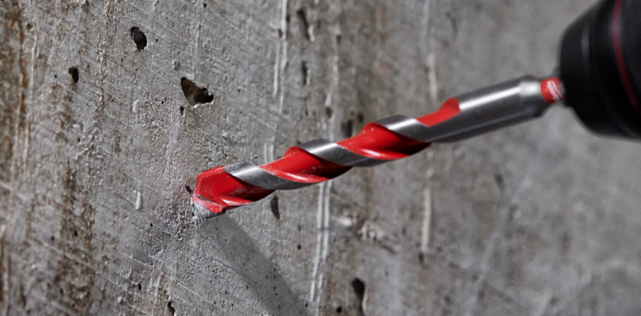 A picture of a carbide drill bit preparing to drill into a concrete wall