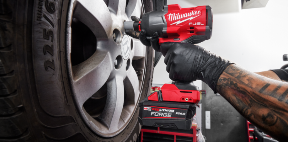 A picture of a person using an impact wrench to tighten bolts on a car tire