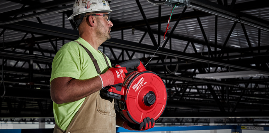 A construction worker using a Milwaukee M18 Fish Tape