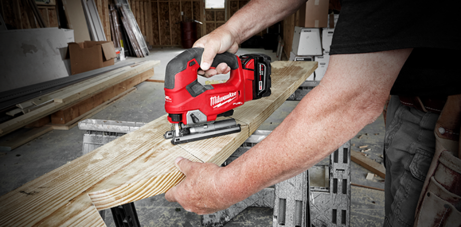 A picture of someone using a jigsaw to cut a piece of wood