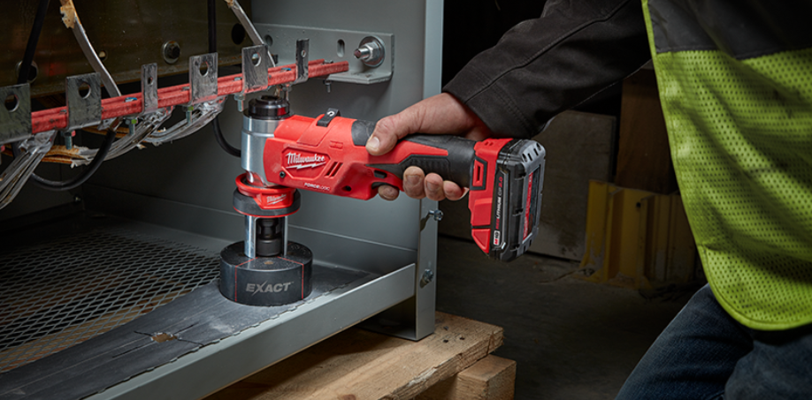 A Milwaukee Knockout tool making a hole in a piece of metal