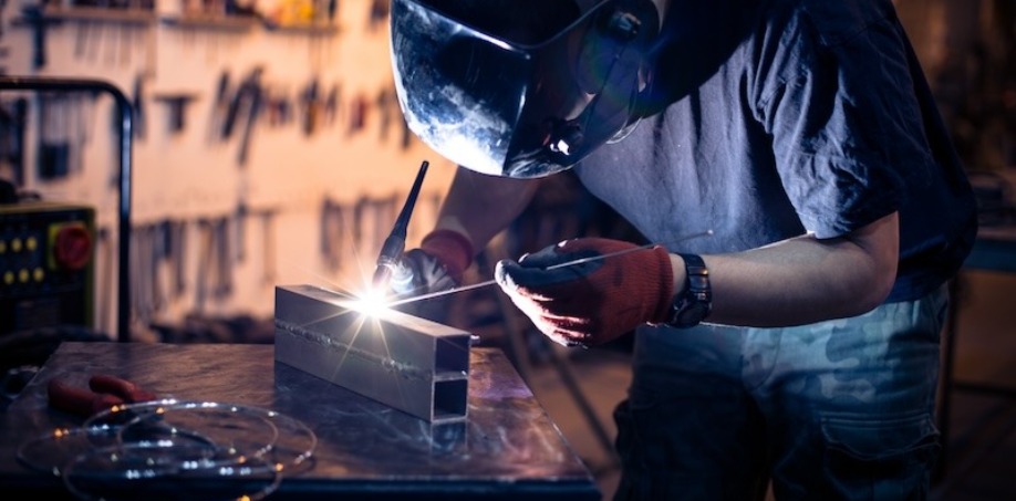 A person TIG welding on a piece of steel