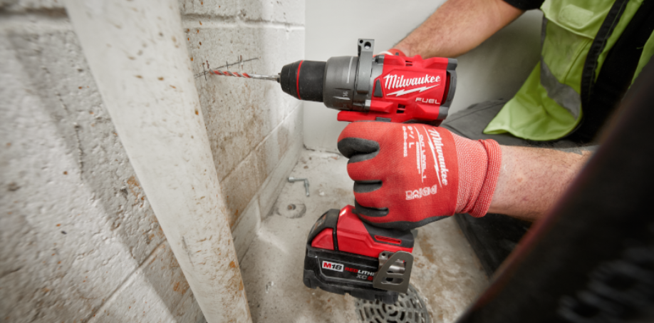 Someone using a Milwaukee Hammer Drill to drill a hole in the wall