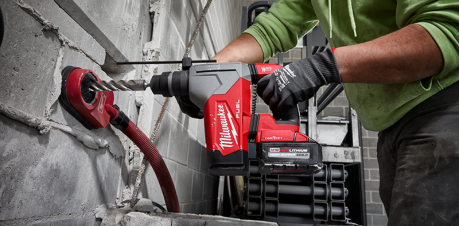 Someone using a Milwaukee rotary hammer to drill through a concrete wall