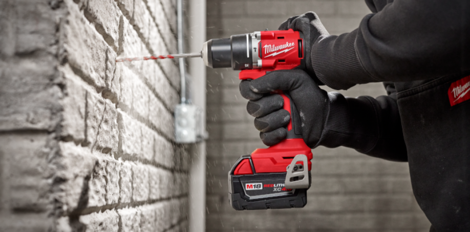 Someone using a Milwaukee Hammer Drill to drill a hole in a concrete wall