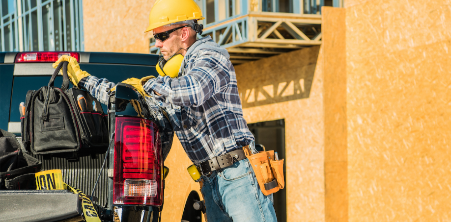 A construction worker grabbing his tool bag out of his truck