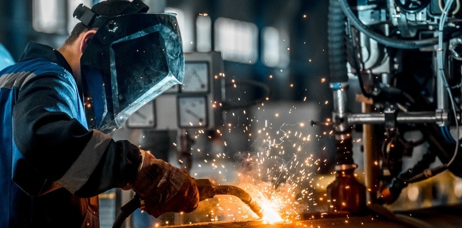 Someone welding a piece of steel wearing a welding helmet